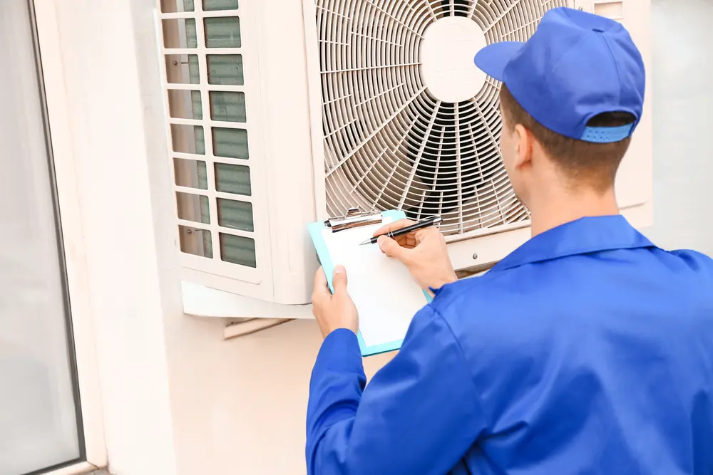 male hvac technician installing outdoor unit of air conditioner