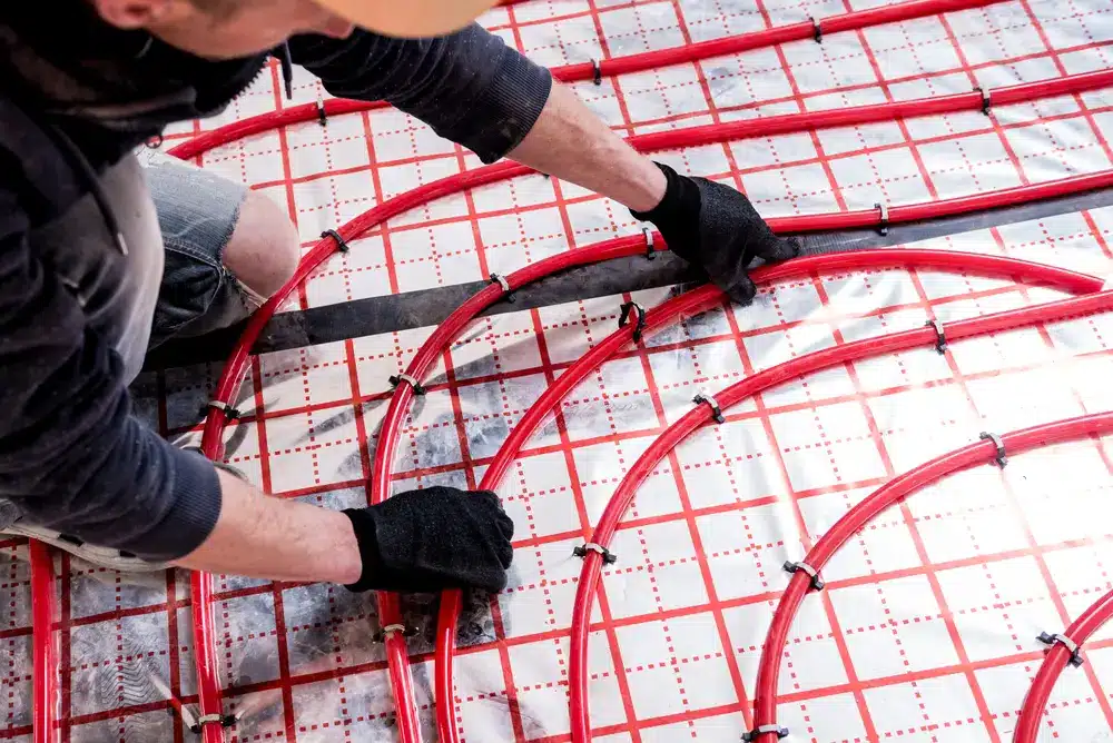 pipefitter installing radiant floor heating system