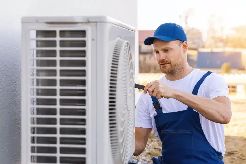 technician working on air conditioning or heat pump outdoor unit. HVAC service, maintenance and repair