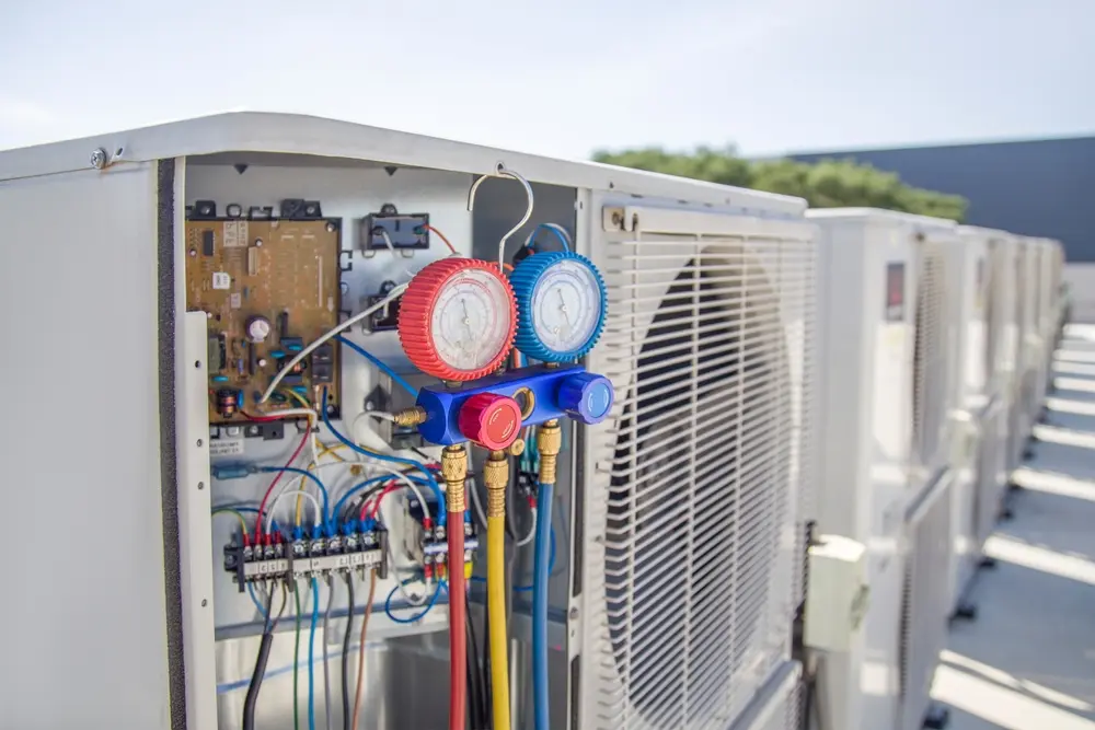 Air conditioning, heat pump, and HVAC service technician using gauges to check refrigerant and add refrigerant.